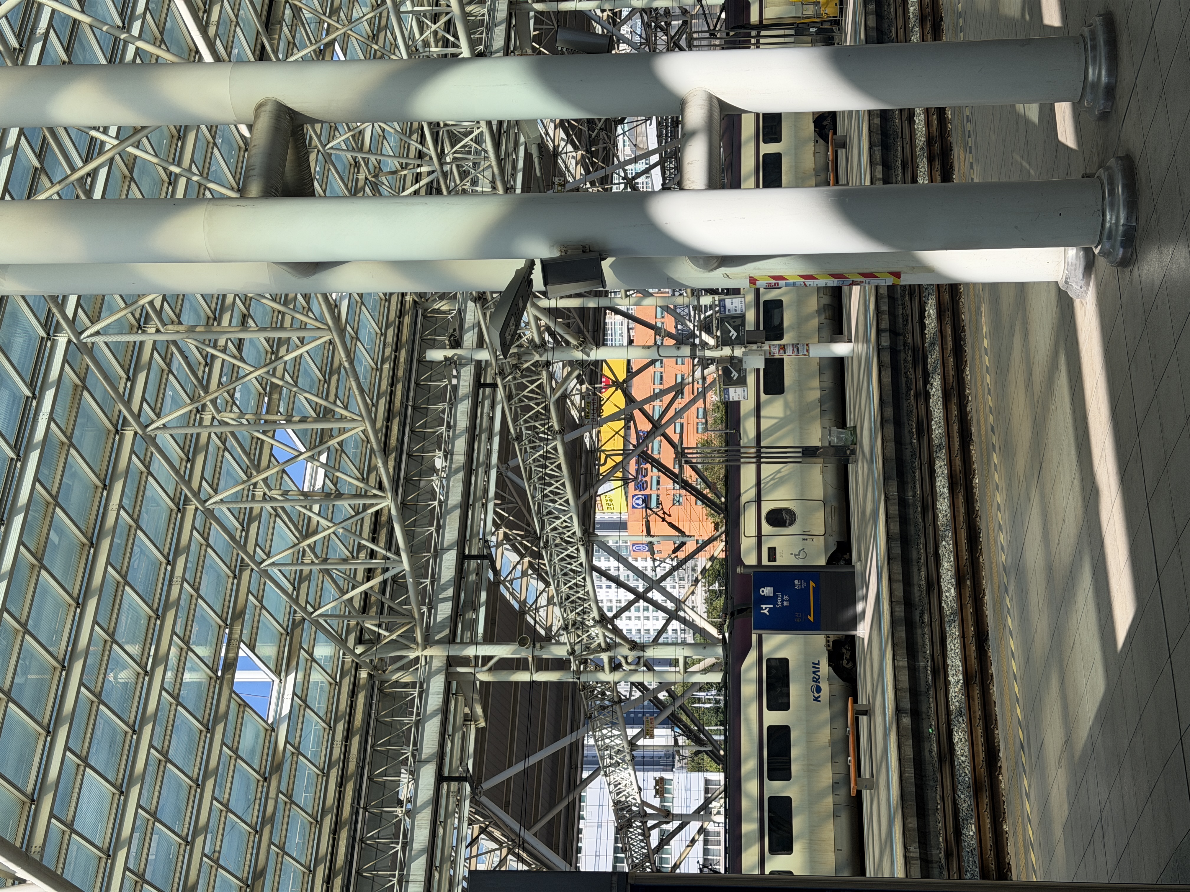A train station platform with a glass ceiling and steel framework